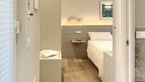 A modern bedroom with a wooden floor, a bed with white bedding, a bedside table, and a nightstand. - "ULIVO" - Equipped suite, on the ground floor, with veranda. (Levanto)