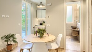 Eine moderne Küche mit einem runden Esstisch, weißen Stühlen und einem Blumentopf.