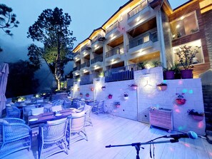 Un hotel con terraza al aire libre, varios balcones y plantas en macetas.