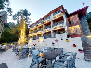 Un hotel de varios pisos con mesas al aire libre y plantas en macetas.