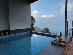 Una piscina infinita moderna con una vista despejada del cielo y árboles lejanos.