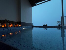 A serene indoor pool area with tiled flooring and potted plants along the wall.
