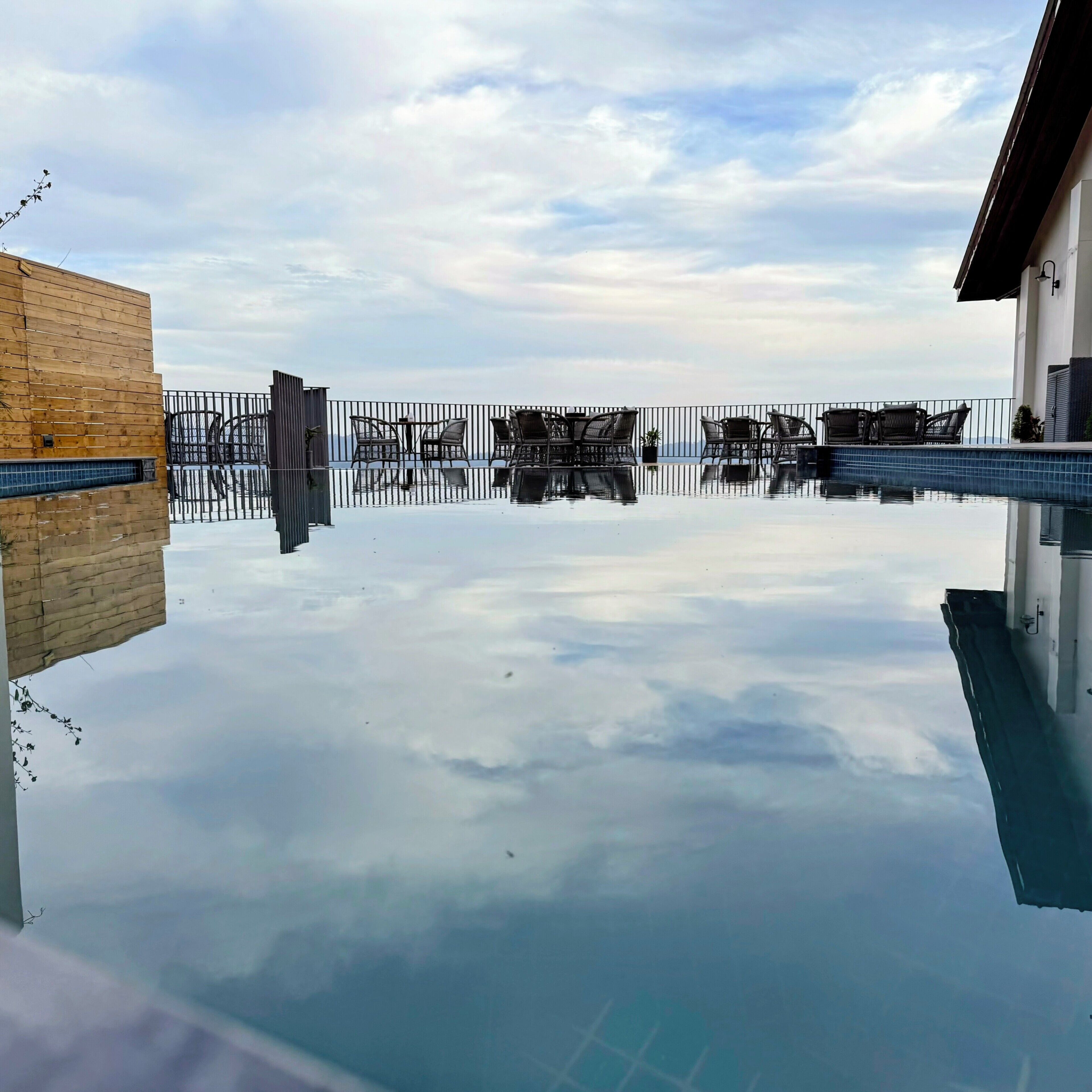 En pool med fri sikt upp mot himlen och en träbyggnad till vänster.
