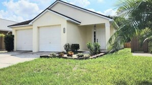 Ein eingeschossiges Haus mit Garage, überdachter Veranda und gepflegtem Rasen.