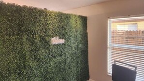 Ein Zimmer mit grüner Wand, einem 'Welcome'-Schild und einem Fenster mit Jalousien.
