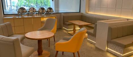 A modern interior with seating arrangements, a counter, and a view of greenery outside.