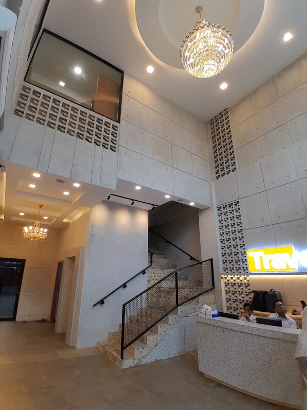 A hotel lobby with a staircase, a reception desk, and a chandelier. - TravelBiz Hotel (Medan)