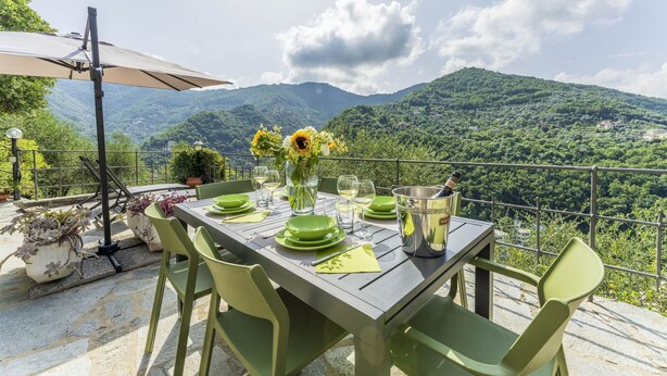 A table set outdoors with a mountain view, green chairs, and a table umbrella. - Apartment in Recco with 1 bedrooms sleeps 4 (Recco)