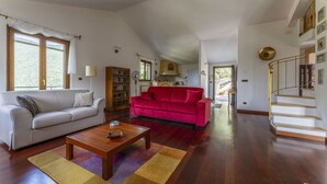 A spacious living room with a white sofa, a red sofa, and a wooden coffee table. There is a bookshelf and a kitchen visible in the background. - Apartment in Recco with 1 bedrooms sleeps 4 (Recco)