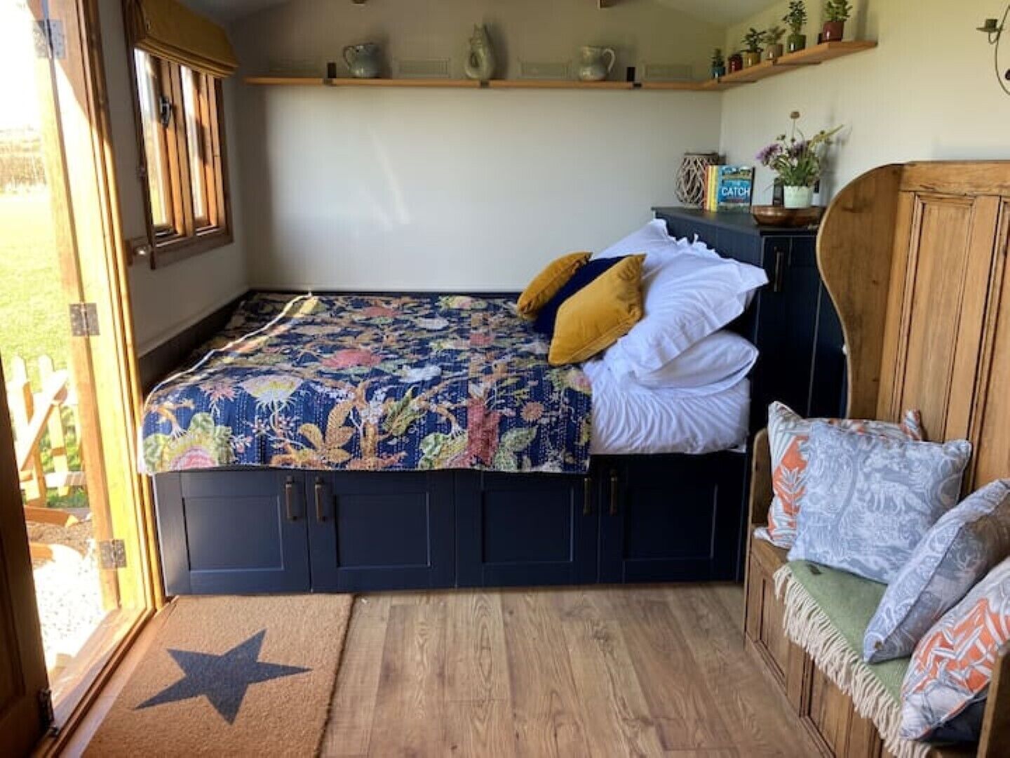 Une chambre confortable avec un lit, une armoire en bois et un banc agrémenté de coussins.