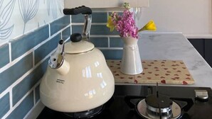 A kitchen with a white kettle, a vase with flowers, and a hanging kitchen tool. - Shepherd Hut in Private Meadow With Outdoor Bath (Langport)