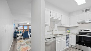 A modern kitchen with white cabinets, a dishwasher, and a stainless steel oven. - La Mirage Condo 206 Beachfront Resort Condominiums with Private Boardwalk to Beach (Port Aransas)