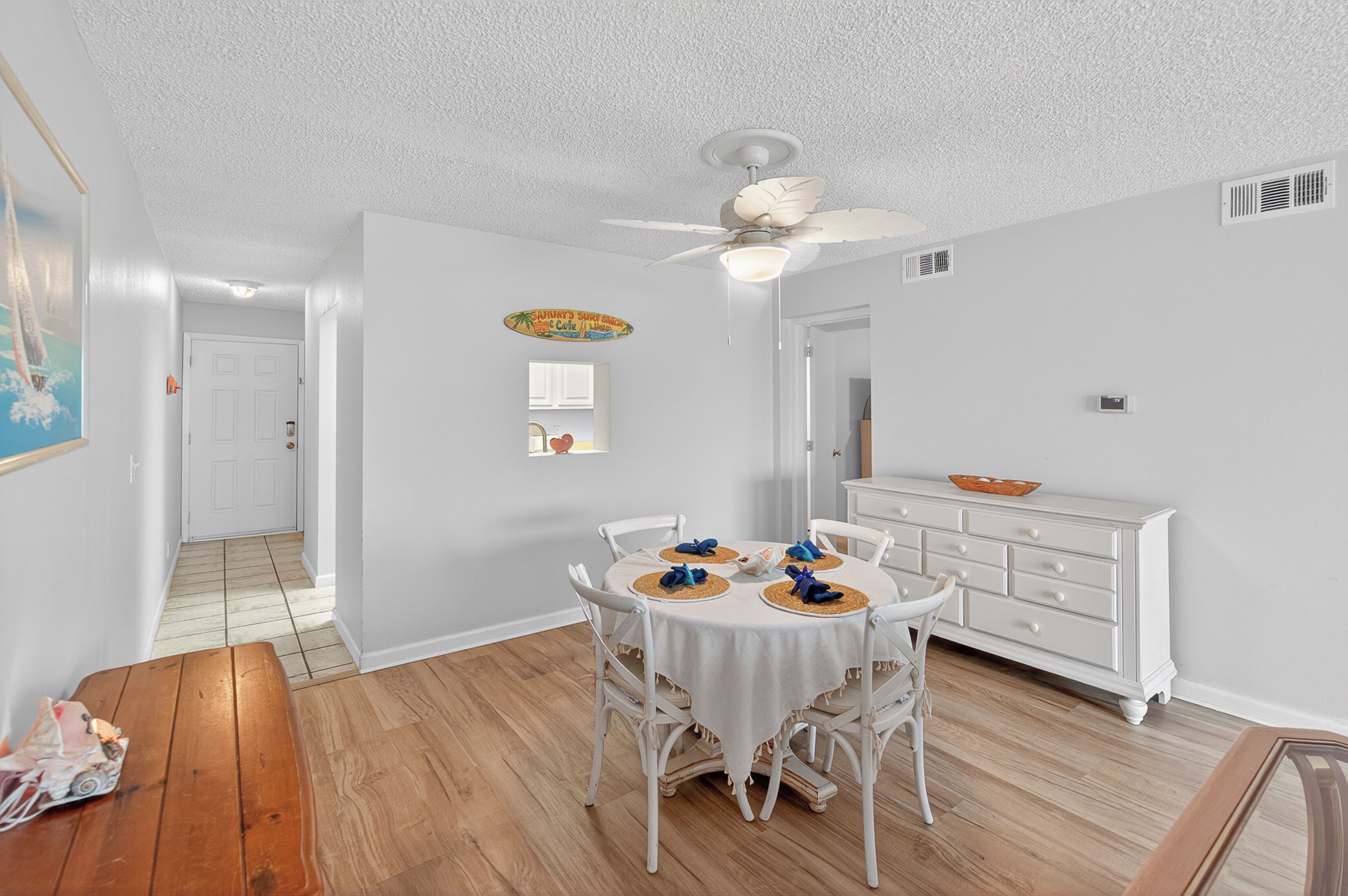 A dining area with a round table, white chairs, and a ceiling fan.