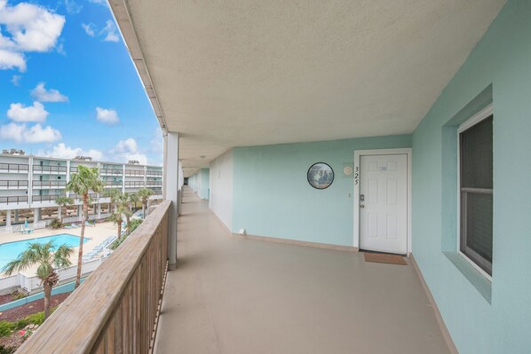 A balcony with a view of a swimming pool and a building complex.