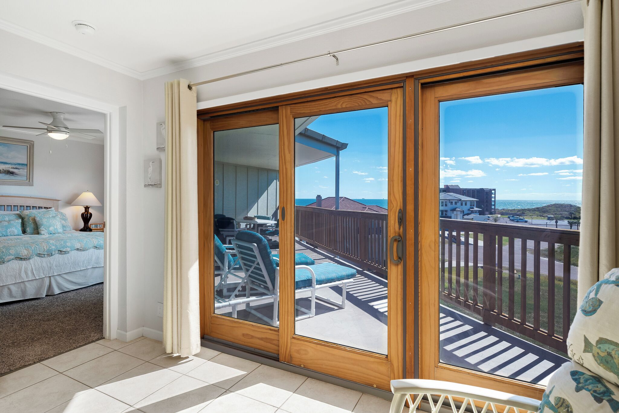 A room with a bed, a balcony with sun loungers, and a view of the sea.