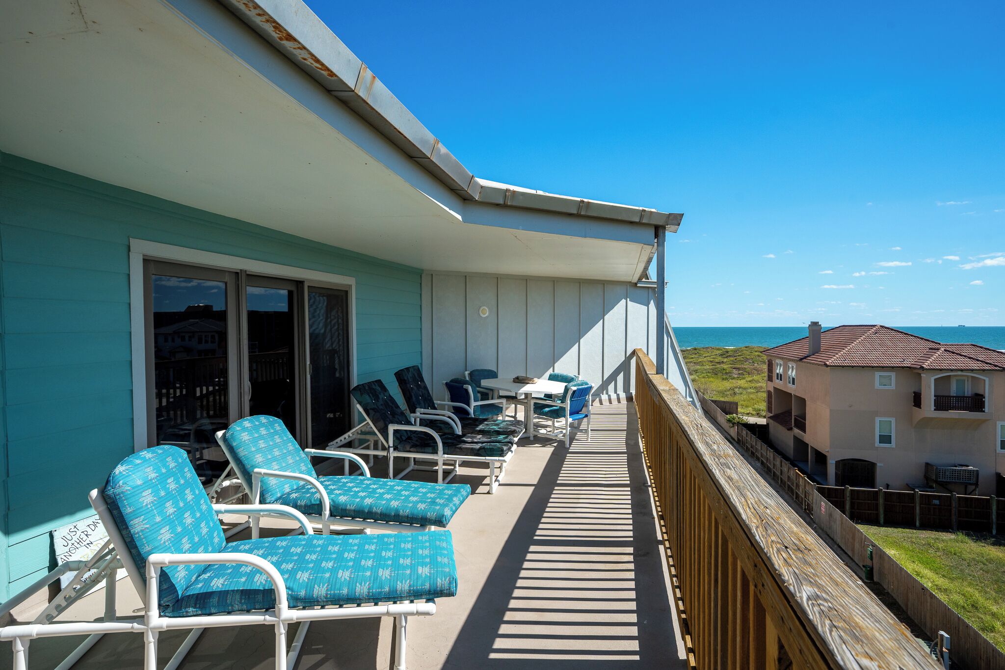 En balkon med loungesenge, et bord og havudsigt.