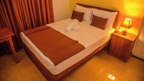 Ein ordentlich bezogenes Bett mit einer braunen Decke, weißen Kissen und einem Holzkopfende.