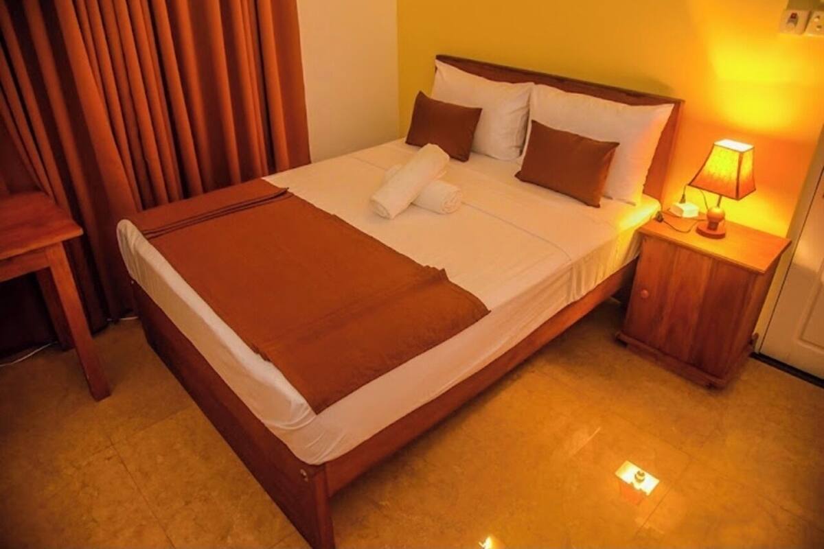 A neatly made bed with a brown blanket, white pillows, and a wooden headboard.