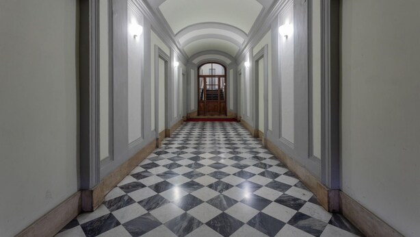A corridor with a checkered floor, white walls, and a wooden door at the end. - Carignano 8 - Turin Central Loft Carignano (Turin)