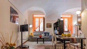 A compact living space with a sofa, dining table, chairs, and a TV. - Carignano 8 - Turin Central Loft Carignano (Turin)