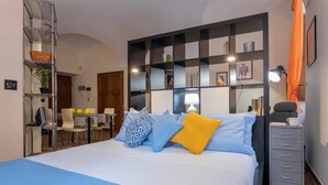 A neatly arranged bedroom with a bed, bedside tables, a desk, and a shelving unit against the wall. - Carignano 8 - Turin Central Loft Carignano (Turin)
