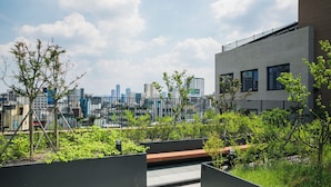 Un jardin sur le toit, agrémenté d’un banc, entouré de verdure et offrant une vue sur la ville.