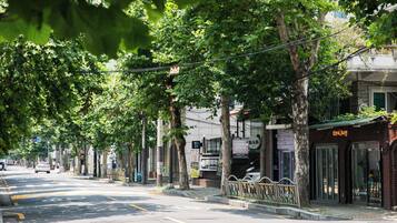 Rua arborizada com um bar e um edifício com uma placa que diz 'Heilung'.