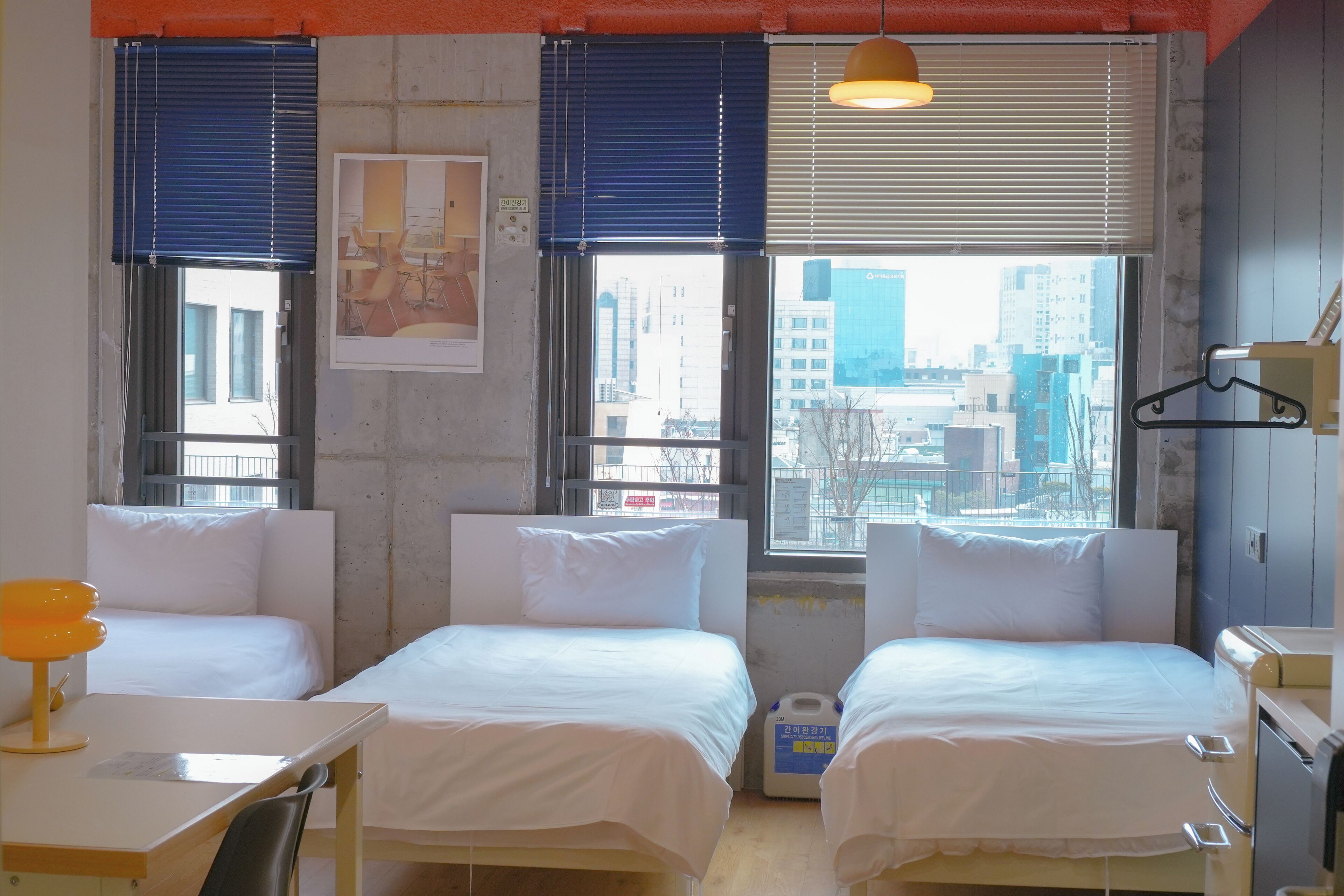 Habitación de hotel con dos camas, un escritorio y una ventana con persianas.