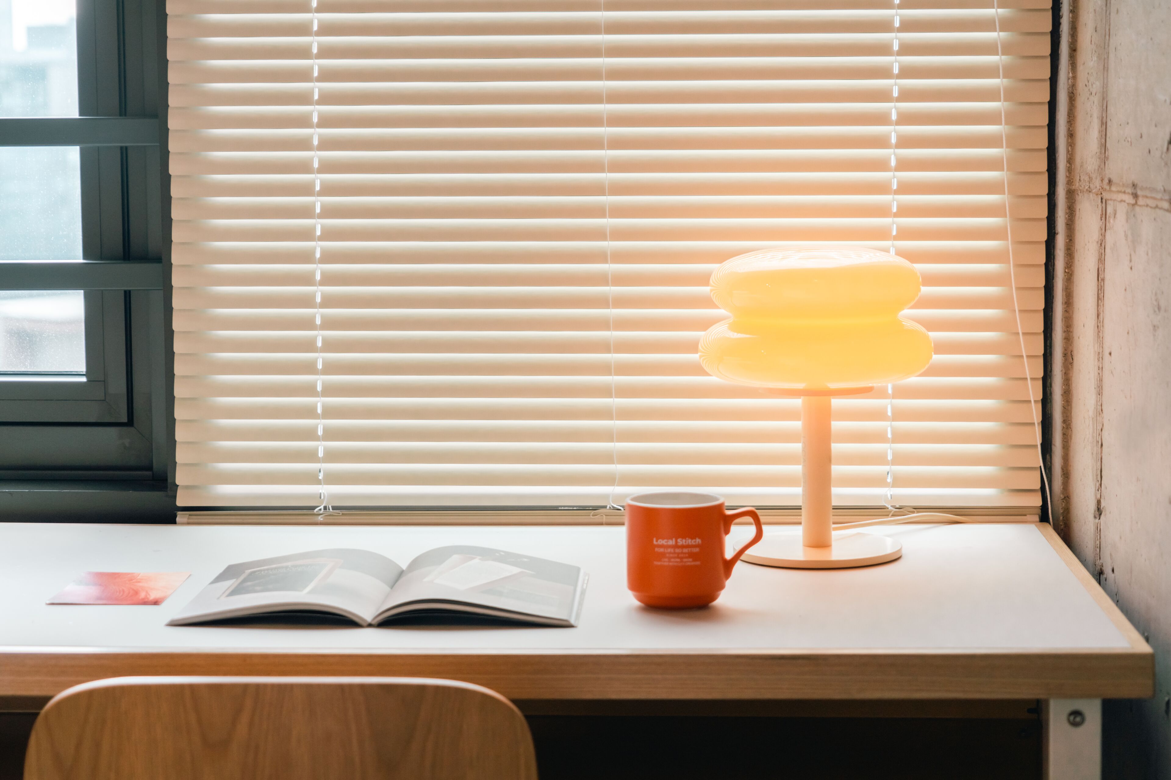 A wooden desk with a lamp, an open book, and a mug.