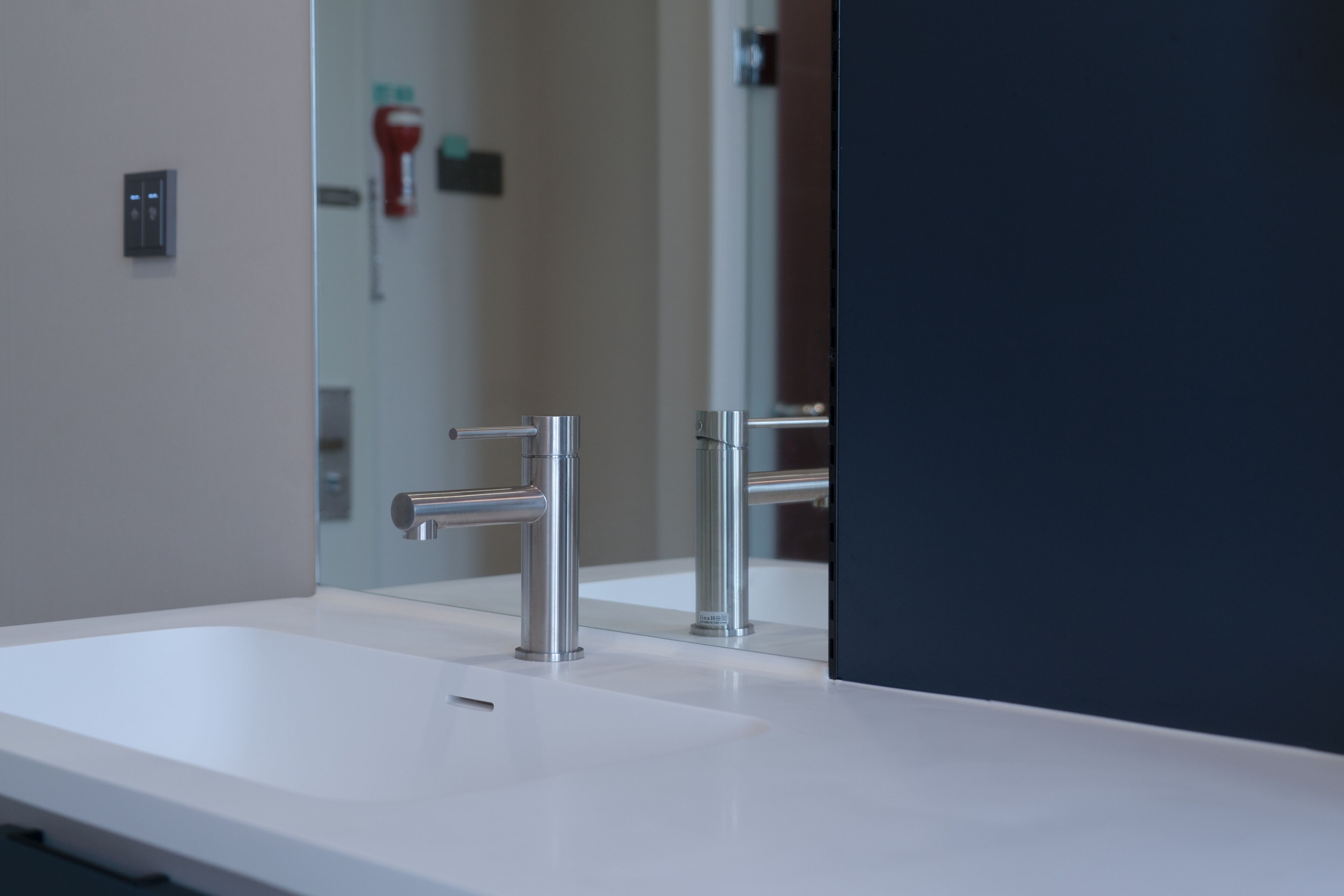 A modern bathroom with a white sink, chrome faucet, and a large mirror.