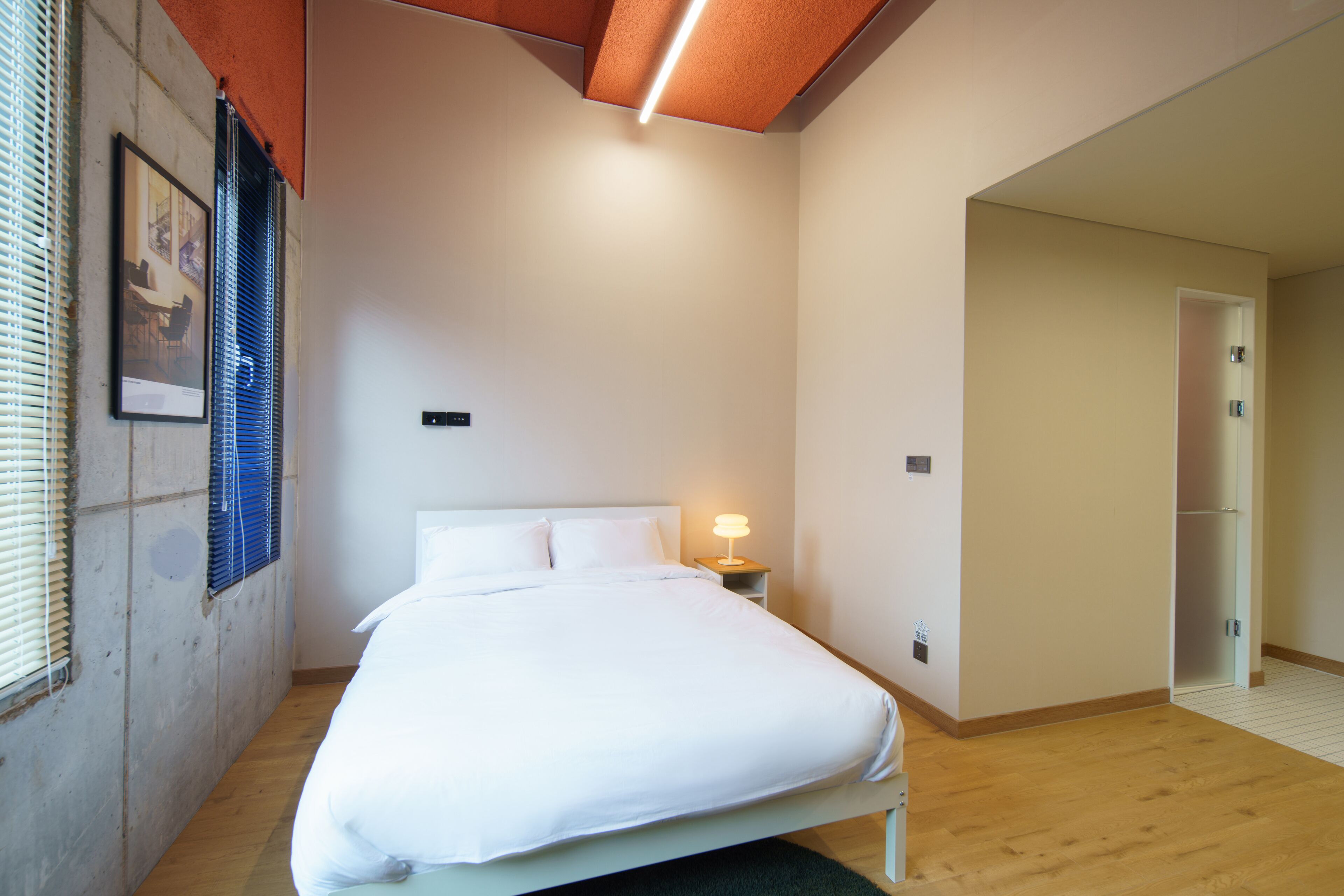 Ein Schlafzimmer mit einem Bett, einer Nachttischlampe und einem gerahmten Bild an der Wand.