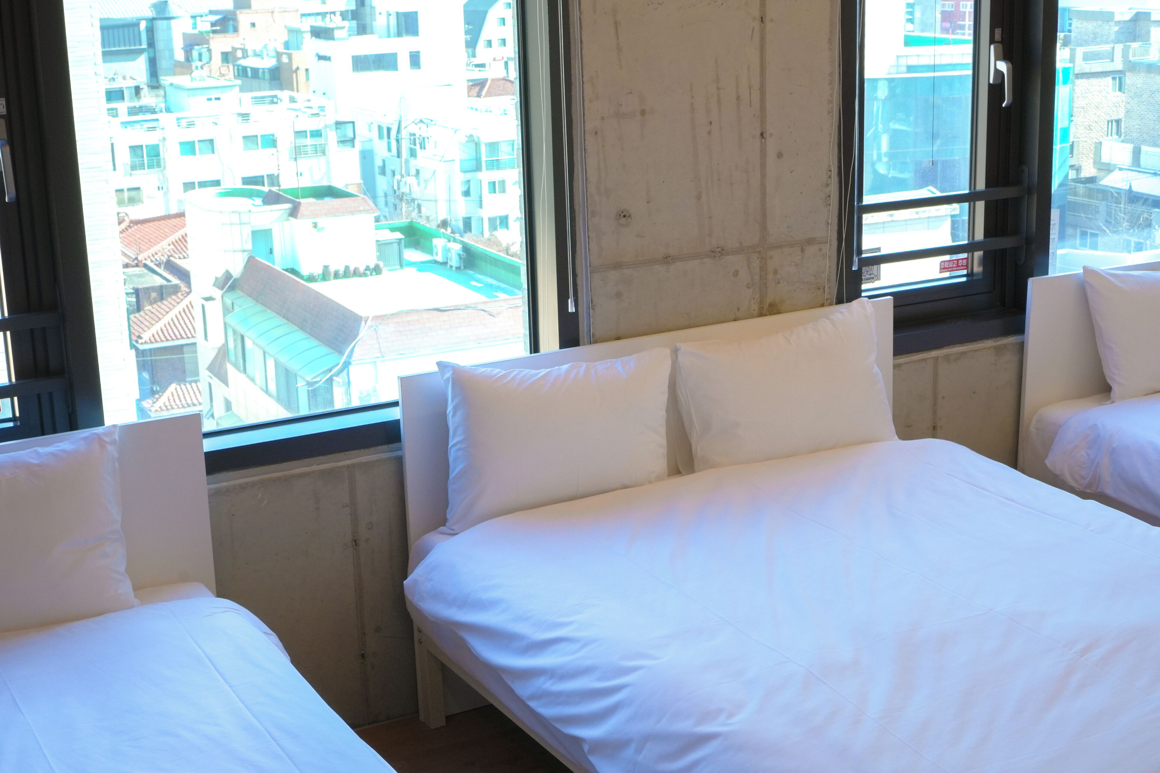A hotel room with two beds, large windows, and a view of the cityscape.