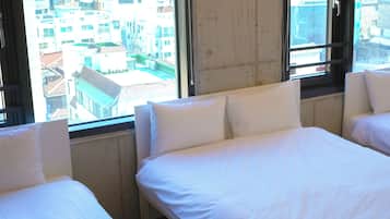 Habitación de hotel con dos camas, ventanas amplias y vistas a la ciudad.