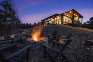 A modern house with a stone fire pit and outdoor seating. - Pool, Hot Tub, Bunkroom, Fire Pit & Chef’s Kitchen| Multi-Story Cabin! (Broken Bow)