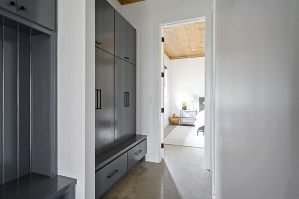A modern interior with a grey wardrobe, a wooden ceiling, and a kitchen area in the background. - Pool, Hot Tub, Bunkroom, Fire Pit & Chef’s Kitchen| Multi-Story Cabin! (Broken Bow)