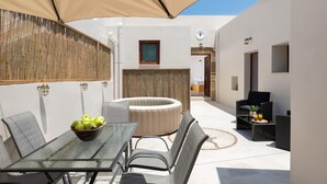 An outdoor patio with a glass table, chairs, a round seating area, and a small table with drinks. - Antica Casa Dei Nonni (Rhodes)