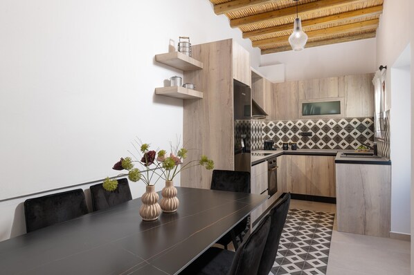 A modern kitchen with wooden cabinets, a black countertop, and a patterned backsplash. - Antica Casa Dei Nonni (Rhodes)