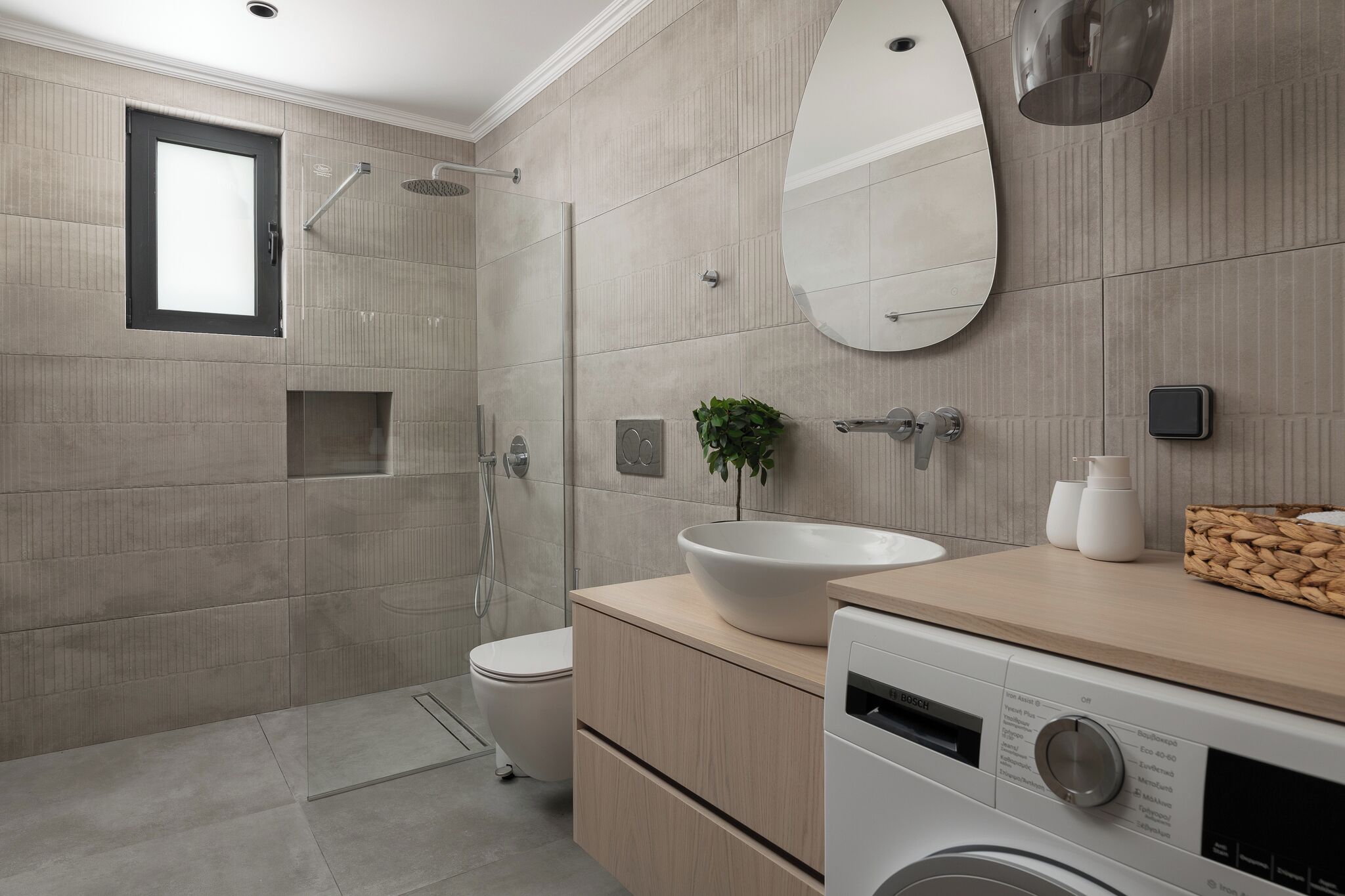 A modern bathroom with a large mirror, a sink, a shower, and a toilet.