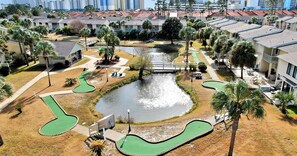 Zona residencial con campo de golf, un pequeño puente y un estanque.