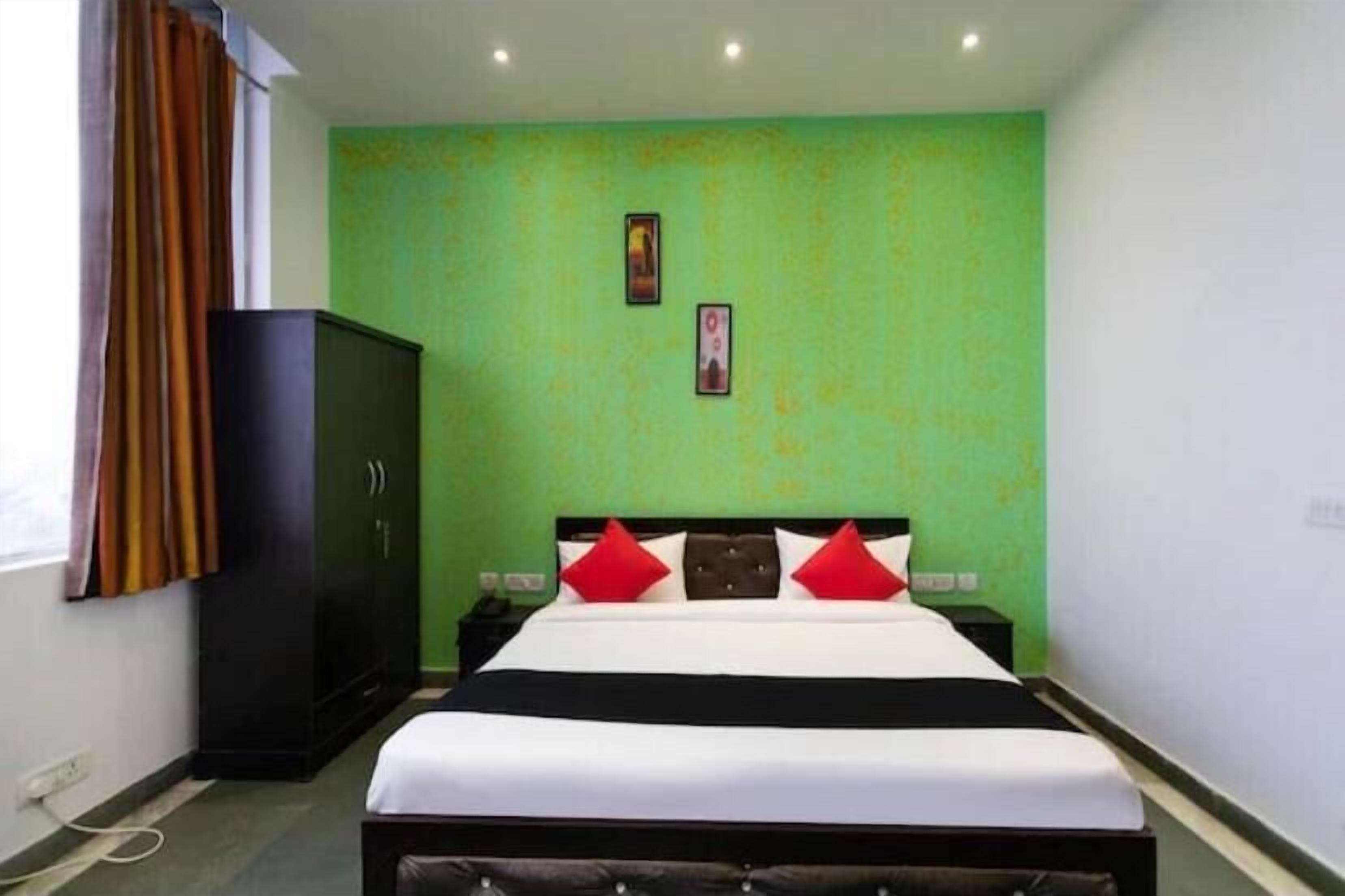 Una habitación de hotel con una cama, un armario y una pared verde.