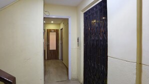 A narrow hallway with a wooden door labeled "302" and a black metal gate on the right. - Hotel Dream inn (Mumbai)