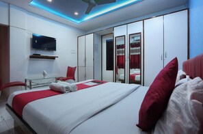 A hotel room with a bed, a TV mounted on the wall, a wardrobe, and a ceiling fan. - Hotel Dream inn (Mumbai)