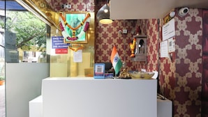 A reception area with a white counter, a framed picture, and an Indian flag. - Hotel Dream inn (Mumbai)
