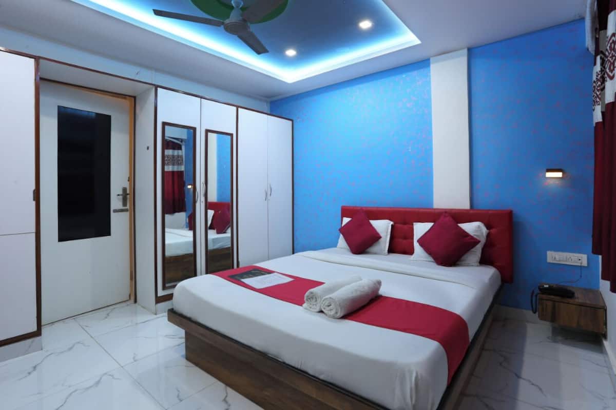 Une chambre d’hôtel moderne, équipée d’un lit, d’une armoire, d’un ventilateur de plafond et décor ée dans des tons rouge et blanc.