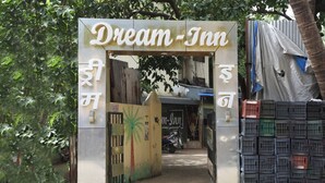 The entrance to Dream-Inn with a palm tree mural and stacked crates. - Hotel Dream inn (Mumbai)