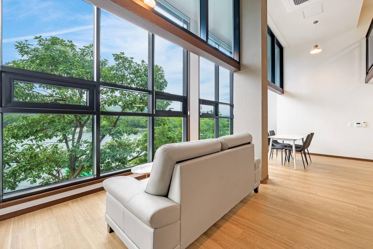 Un interior moderno con ventanas amplias, un sofá, una mesa de comedor y sillas.