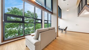 Un interior moderno con ventanas amplias, un sofá, una mesa de comedor y sillas.