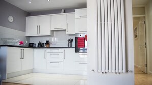 Una cocina moderna con armarios blancos, encimera negra y una toalla roja colgada del horno.