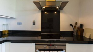 A modern kitchen with a black countertop, stainless steel appliances, and a glass range hood. - Grande Central Sandyford (Dublin)