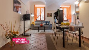 A compact living space with a sofa, dining table, and chairs, a TV, and a bookshelf. - Turin Central Loft Carignano by Wonderful Italy (Torino)